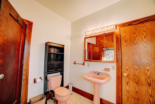 bathroom with baseboards, a sink, toilet, and tile patterned floors