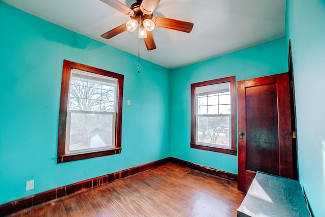 empty room featuring a ceiling fan, baseboards, and wood finished floors