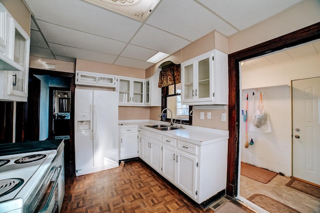 kitchen featuring light countertops, glass insert cabinets, white cabinetry, a sink, and white appliances