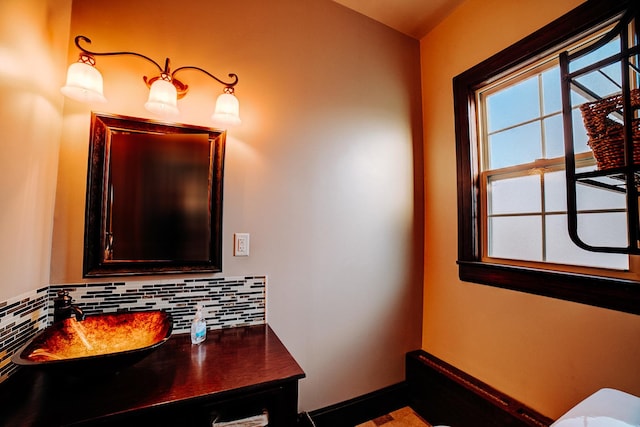 bathroom with tasteful backsplash, a sink, and baseboards