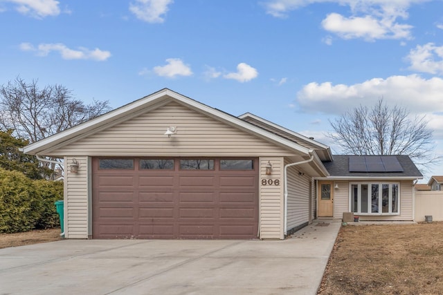 ranch-style house with a garage, solar panels, and driveway