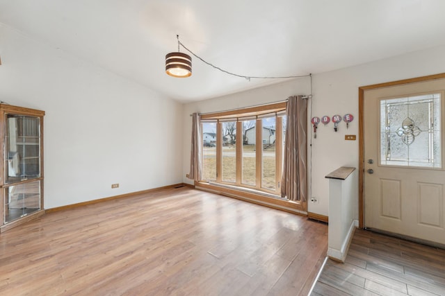 entryway with vaulted ceiling, light wood-type flooring, and baseboards