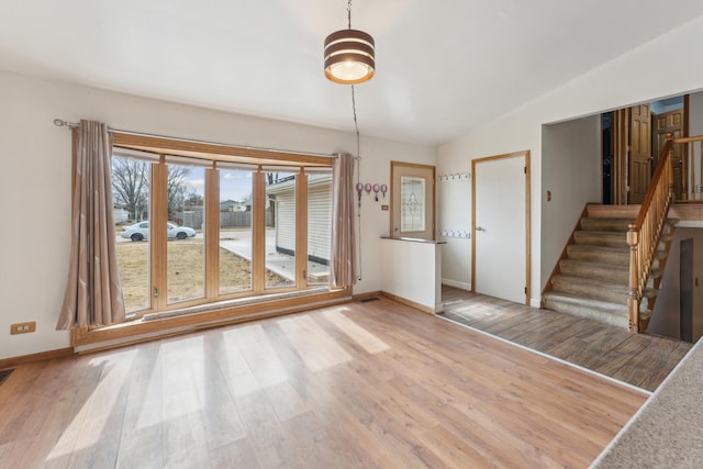 interior space featuring lofted ceiling, stairs, baseboards, and wood finished floors