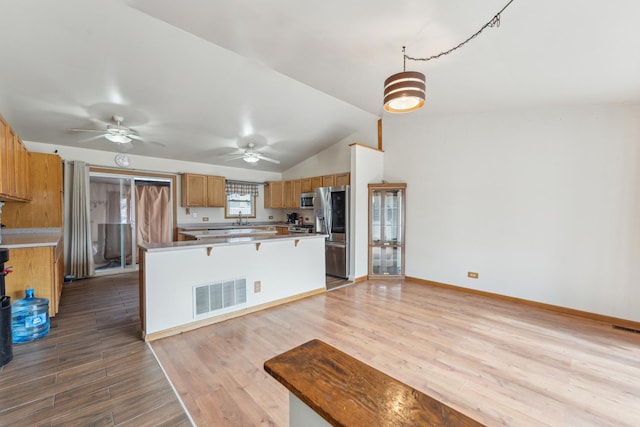 kitchen with a breakfast bar area, visible vents, appliances with stainless steel finishes, a sink, and wood finished floors