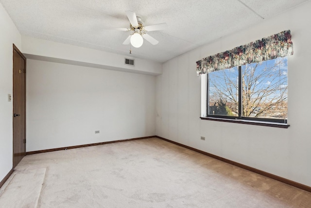 unfurnished room featuring visible vents, a ceiling fan, a textured ceiling, baseboards, and light colored carpet