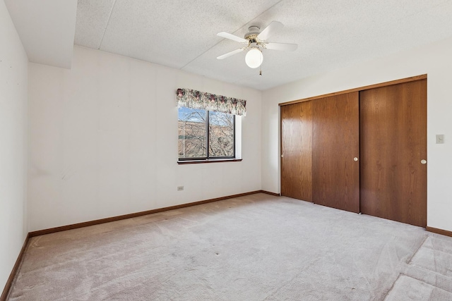 unfurnished bedroom featuring carpet flooring, baseboards, a closet, and a textured ceiling