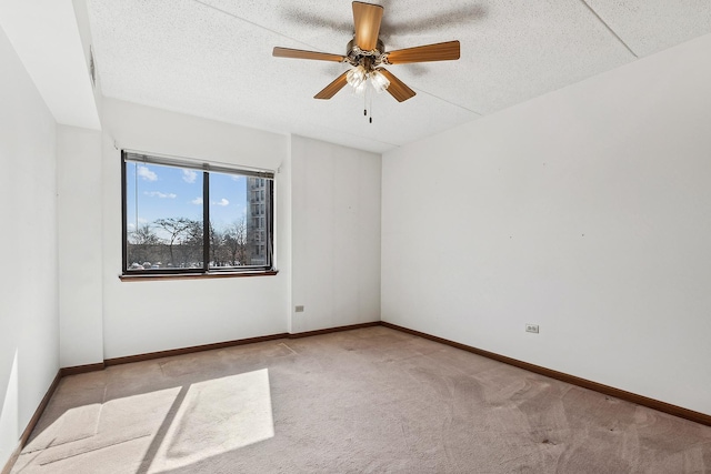 empty room with a textured ceiling, a ceiling fan, baseboards, and carpet floors