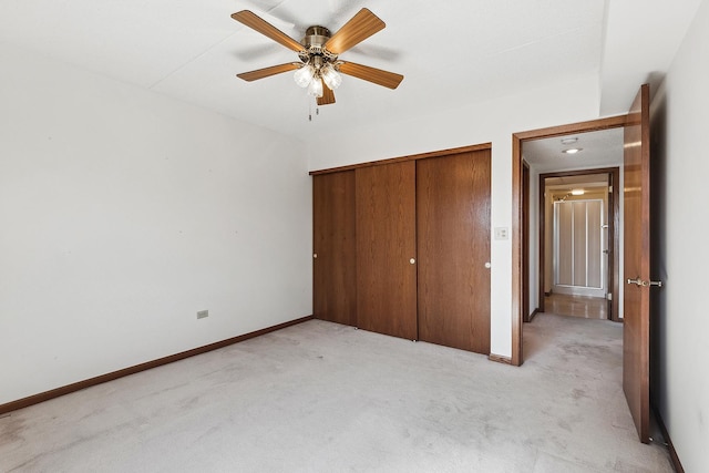 unfurnished bedroom featuring a closet, baseboards, and light colored carpet