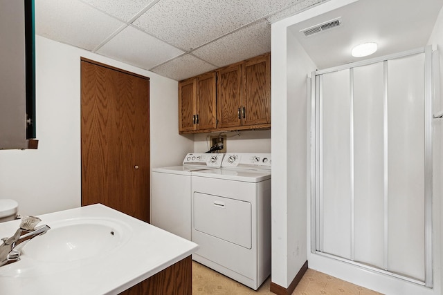 clothes washing area with visible vents, washer and clothes dryer, a sink, cabinet space, and light floors