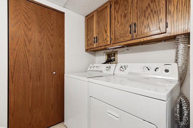 clothes washing area with washing machine and clothes dryer and cabinet space