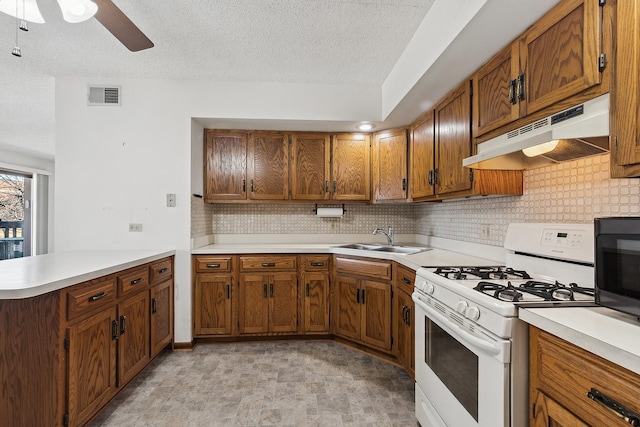 kitchen with visible vents, white gas stove, a sink, black microwave, and under cabinet range hood