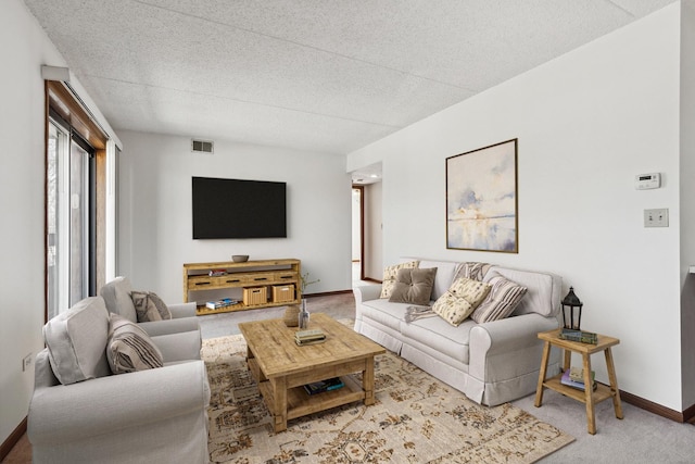 carpeted living room with visible vents, a textured ceiling, and baseboards