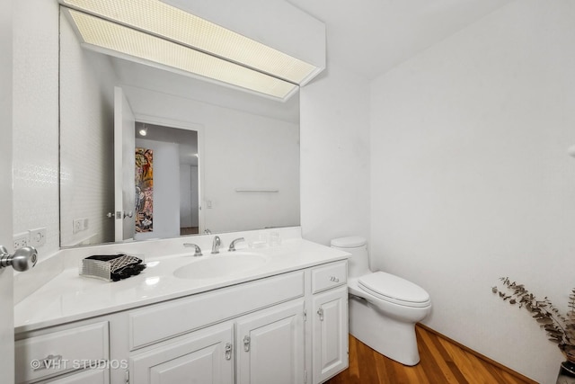 bathroom featuring toilet, wood finished floors, and vanity