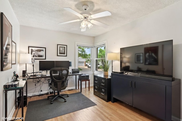 office area featuring baseboards, a textured ceiling, light wood-style flooring, and a ceiling fan