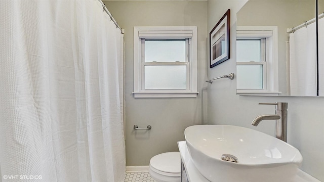 full bathroom with toilet, baseboards, a wealth of natural light, and a sink