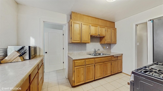 kitchen featuring a sink, decorative backsplash, gas range oven, and light countertops