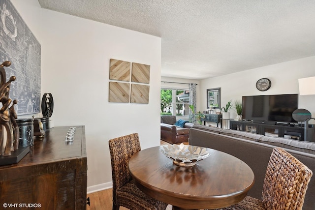 dining area with wood finished floors, baseboards, and a textured ceiling