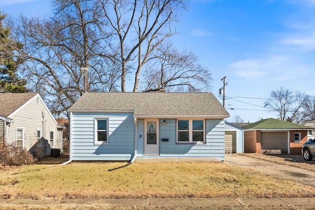 view of front of property with central air condition unit, a shingled roof, and a front yard