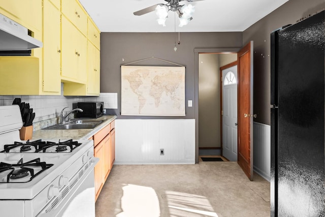 kitchen featuring tasteful backsplash, light countertops, a sink, under cabinet range hood, and black appliances