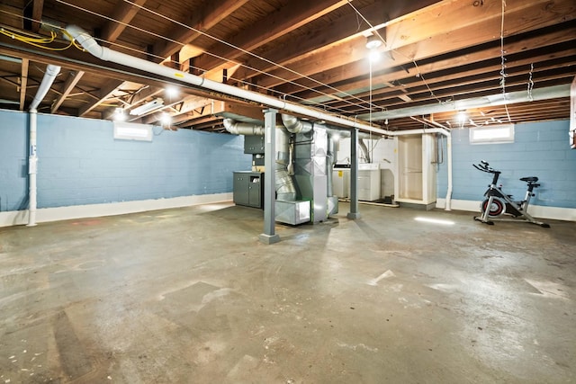 basement with concrete block wall, washer / clothes dryer, and heating unit