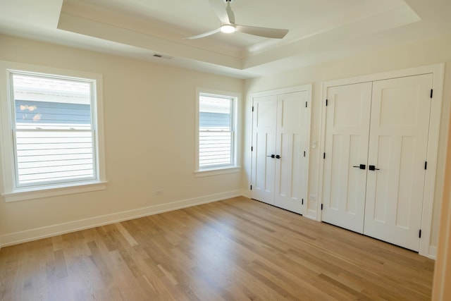 591 S Saylor Ave, Elmhurst, IL 60126 - unfurnished bedroom with visible vents, multiple closets, baseboards, a tray ceiling, and light wood-style flooring