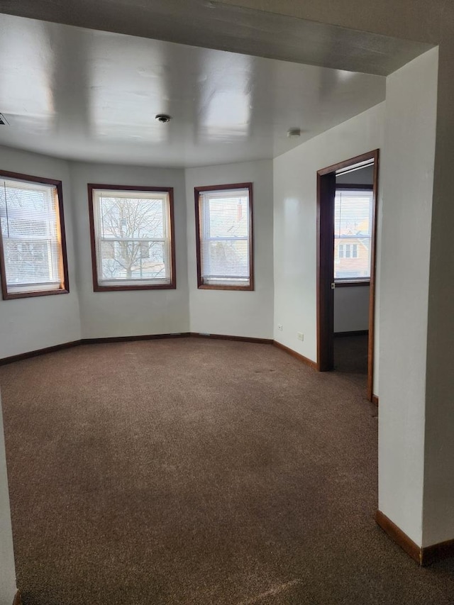 empty room featuring carpet and baseboards