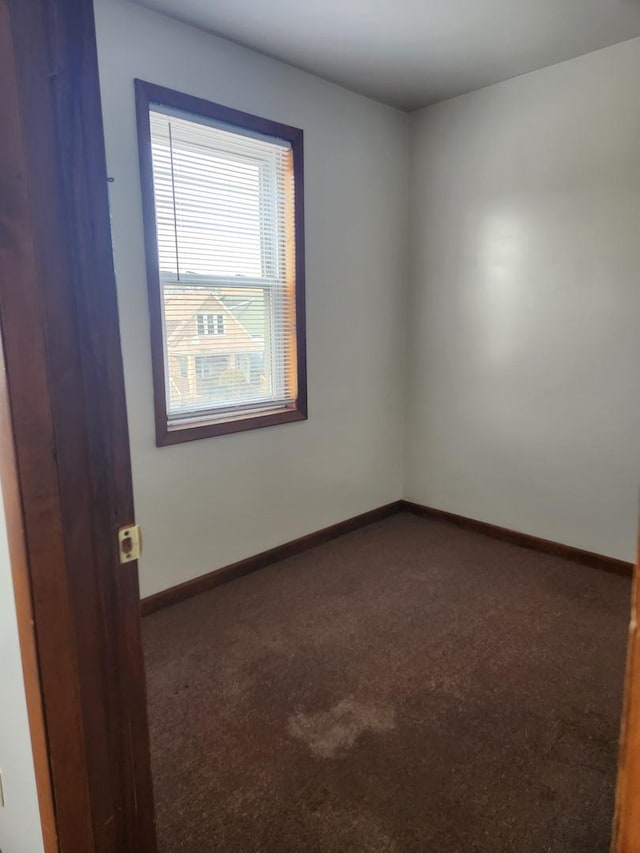 carpeted empty room featuring baseboards