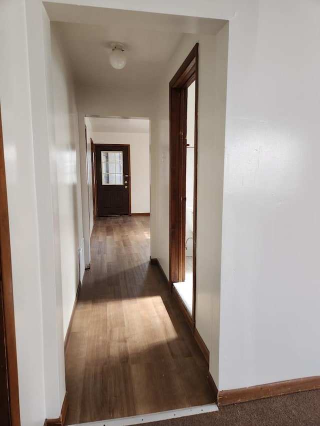 hallway featuring baseboards and wood finished floors