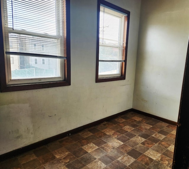 unfurnished room featuring stone finish flooring and baseboards