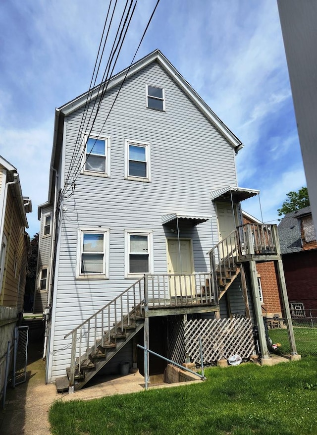 rear view of property featuring stairs, fence, a lawn, and a wooden deck