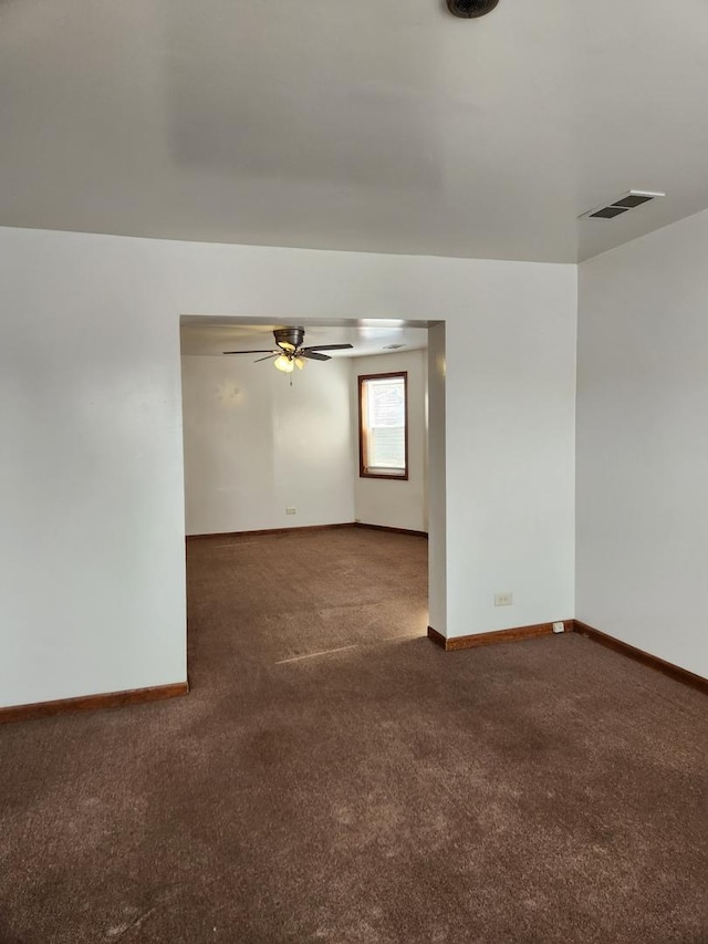 empty room with baseboards, visible vents, ceiling fan, and carpet flooring