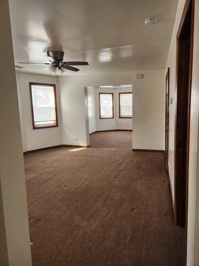 unfurnished room featuring a ceiling fan, a wealth of natural light, carpet flooring, and baseboards