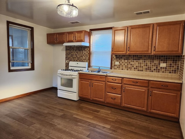 kitchen featuring light countertops, white range with gas stovetop, visible vents, and decorative backsplash