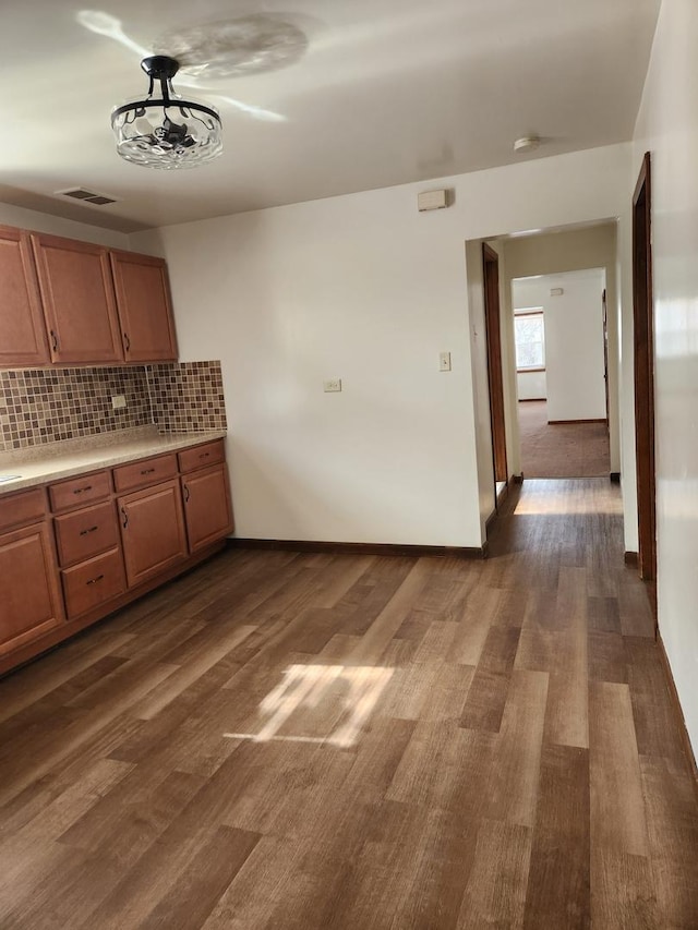 kitchen with tasteful backsplash, visible vents, baseboards, dark wood-style flooring, and light countertops