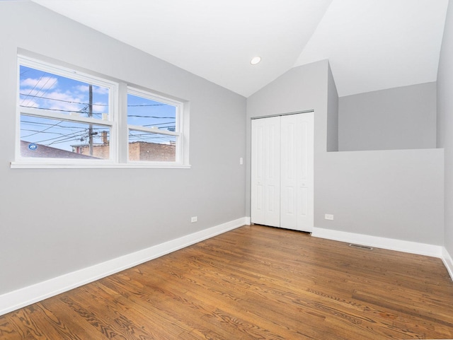 unfurnished bedroom with baseboards, vaulted ceiling, and wood finished floors