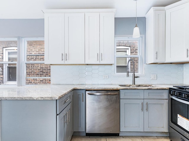 kitchen with decorative backsplash, appliances with stainless steel finishes, light stone countertops, gray cabinets, and a sink