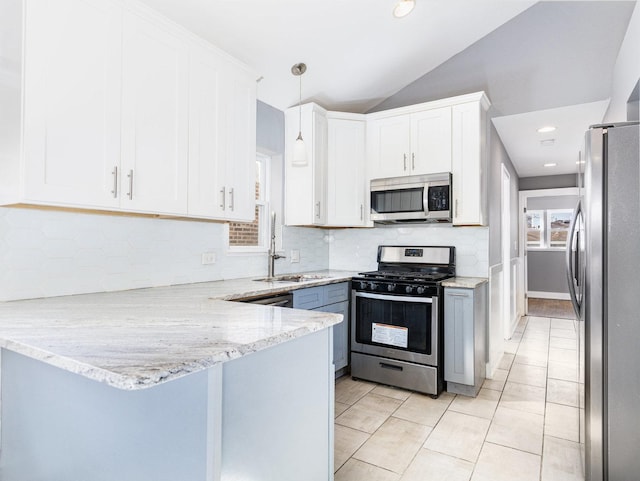 kitchen featuring appliances with stainless steel finishes, white cabinets, vaulted ceiling, light stone countertops, and a peninsula