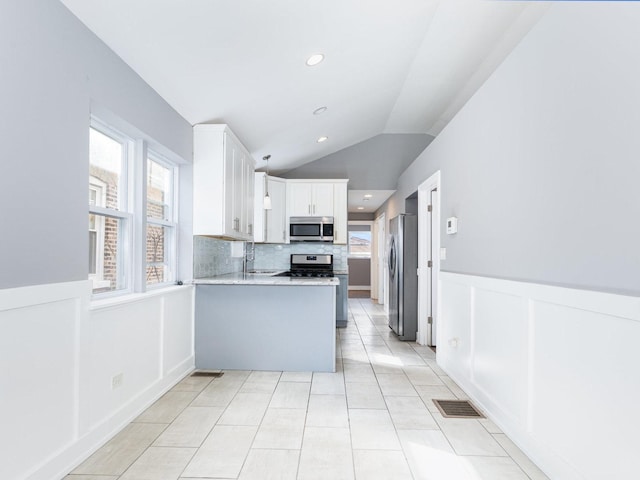 kitchen with a peninsula, a healthy amount of sunlight, visible vents, and appliances with stainless steel finishes