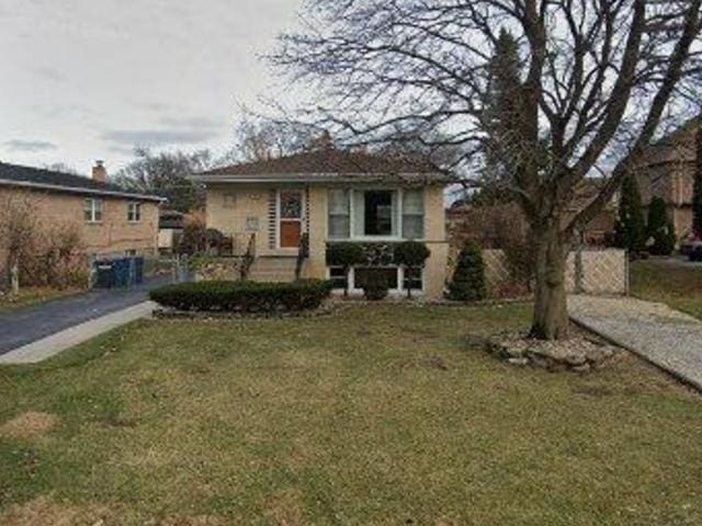 bungalow-style house with driveway, fence, and a front lawn