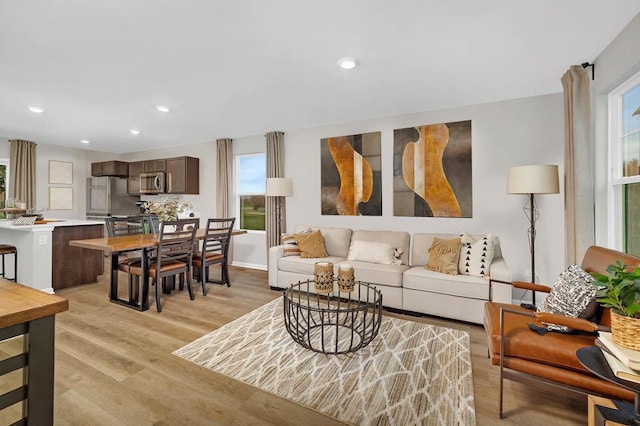 living area featuring light wood-style flooring, baseboards, and recessed lighting