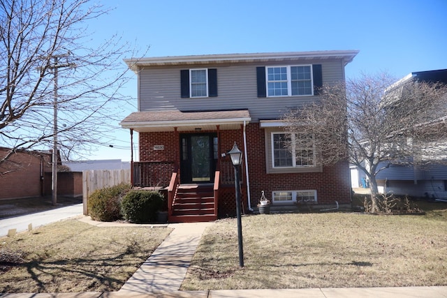 traditional-style house with a front yard, brick siding, and fence