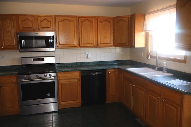 kitchen featuring stainless steel appliances, dark countertops, tasteful backsplash, brown cabinetry, and a sink