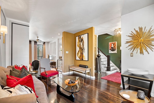 living room featuring stairs, a chandelier, baseboards, and wood finished floors