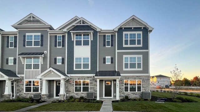 view of front of home featuring cooling unit, a standing seam roof, metal roof, and a front yard