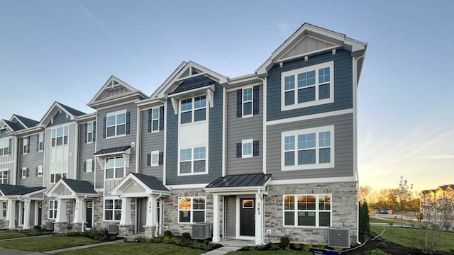 view of front of property featuring central AC, a yard, a standing seam roof, and metal roof