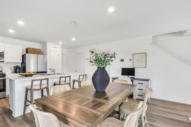 dining area with baseboards, wood finished floors, and recessed lighting