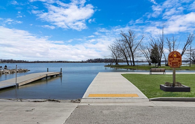 view of dock featuring a lawn and a water view
