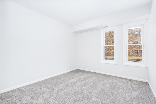 carpeted spare room with visible vents and baseboards