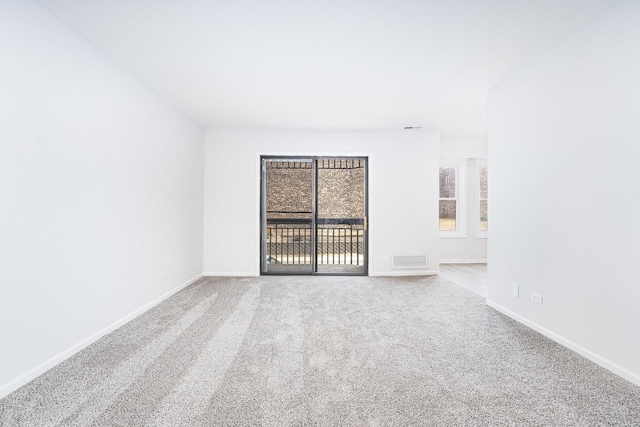 carpeted spare room featuring visible vents and baseboards