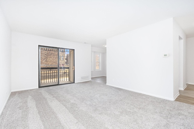 spare room featuring carpet, visible vents, and baseboards